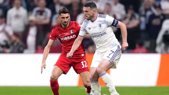 John McGinn of Aston Villa controls the ball while under pressure from Vincenzo Grifo