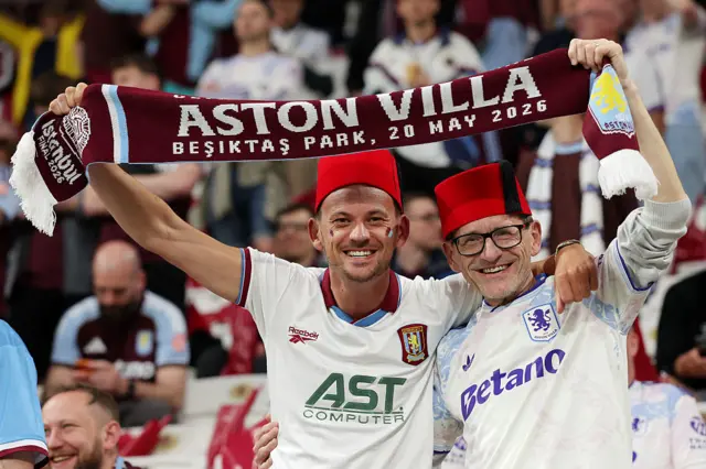 Villa fans wear Fez hats and wave a club scarf with 'Istanbul 26' written on it