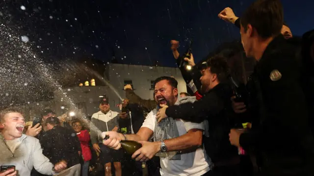 Arsenal fans celebrate with champagne outside the Emirates