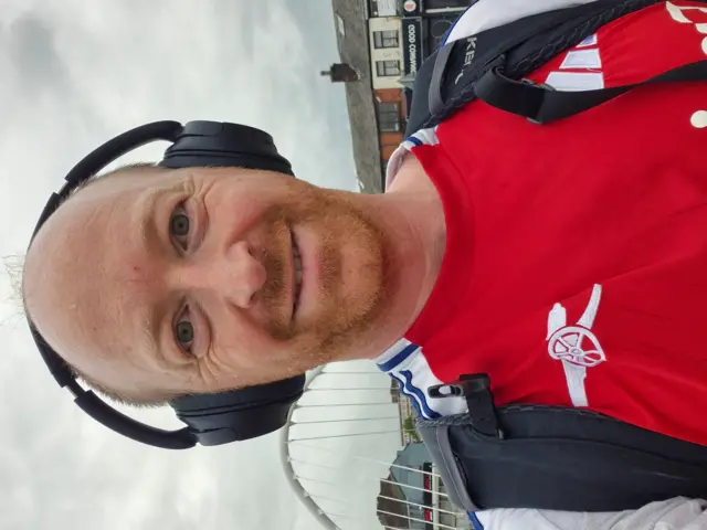 Man wearing Arsenal shirt and headphones