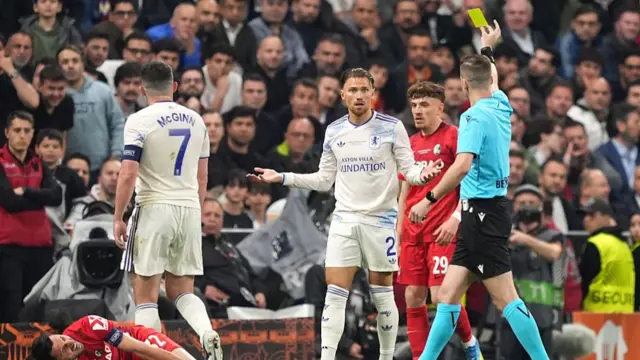 Matty Cash of Aston Villa is shown a yellow card by Referee Francois Letexier