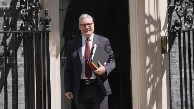 Starmer holds a number of folders as he walks out of Number 10