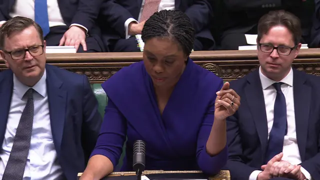 Kemi Badenoch holds her arm up as she speaks in the House of Commons