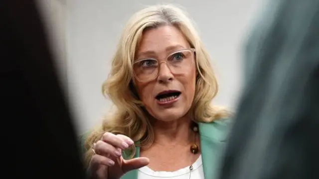 Gillian Martin, a woman with curly blonde hair. She is wearing glasses and a green blazer.