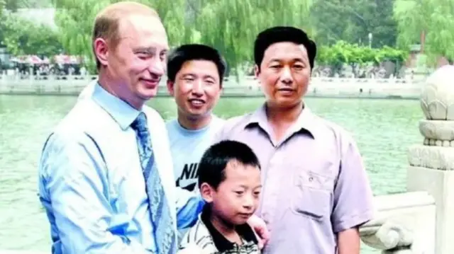 Putin poses for a photo with a boy and two men
