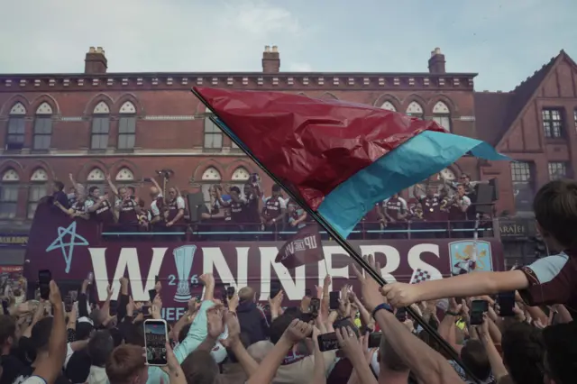 Aston Villa players on a bus celebrating with fans down below them.