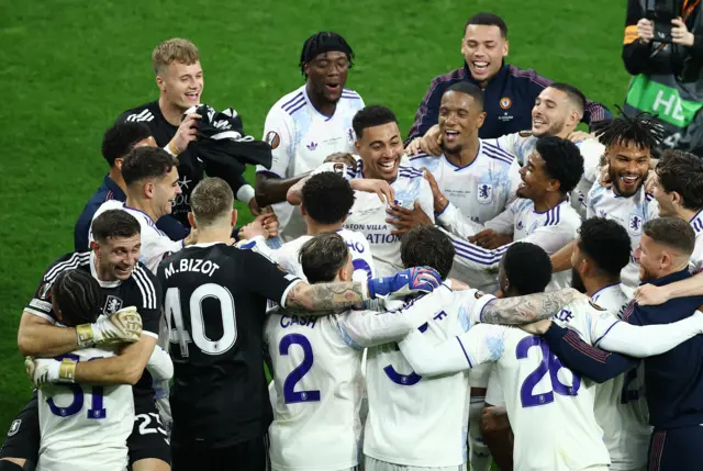 The Villa squad hug in a tight circle as they celebrate