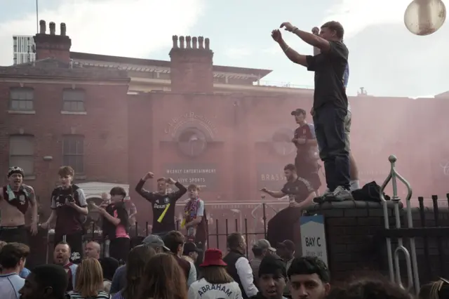 Aston Villa fans celebrate in Birmingham as red flare smoke covers the area.