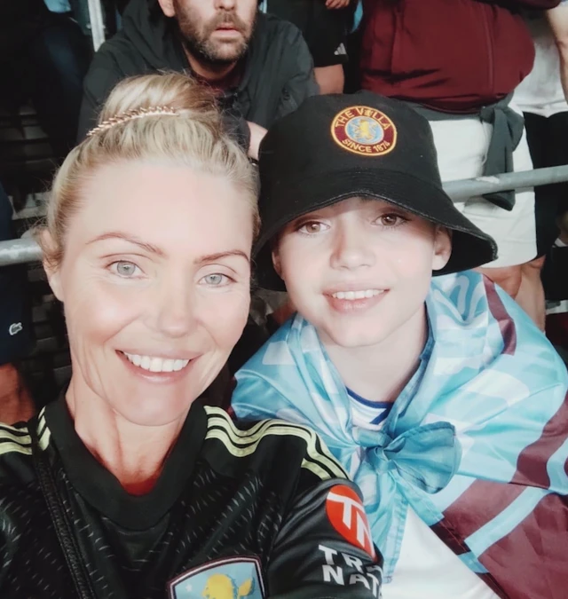 Anna and son Finlay at the stadium in Istanbul. She is wearing a black Villa top and he is wearing a black hat with a flag tied around his shoulders