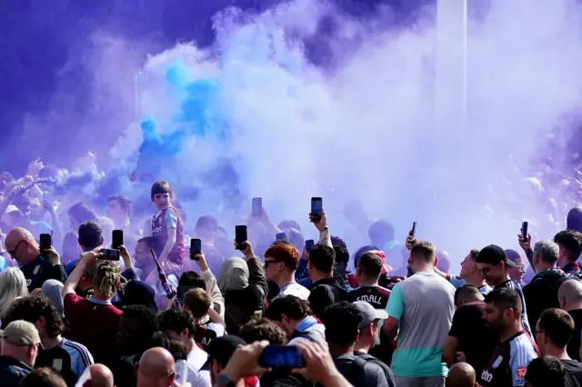 Blue and white flares have been let off and phones are held up as fans gather for Aston Villa's parade