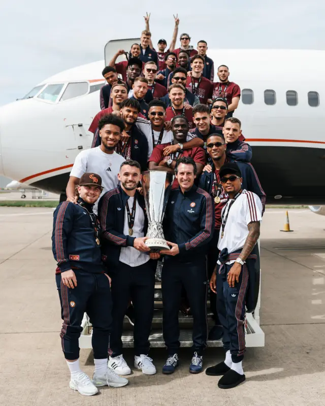 Villa squad poses on plane steps with trophy