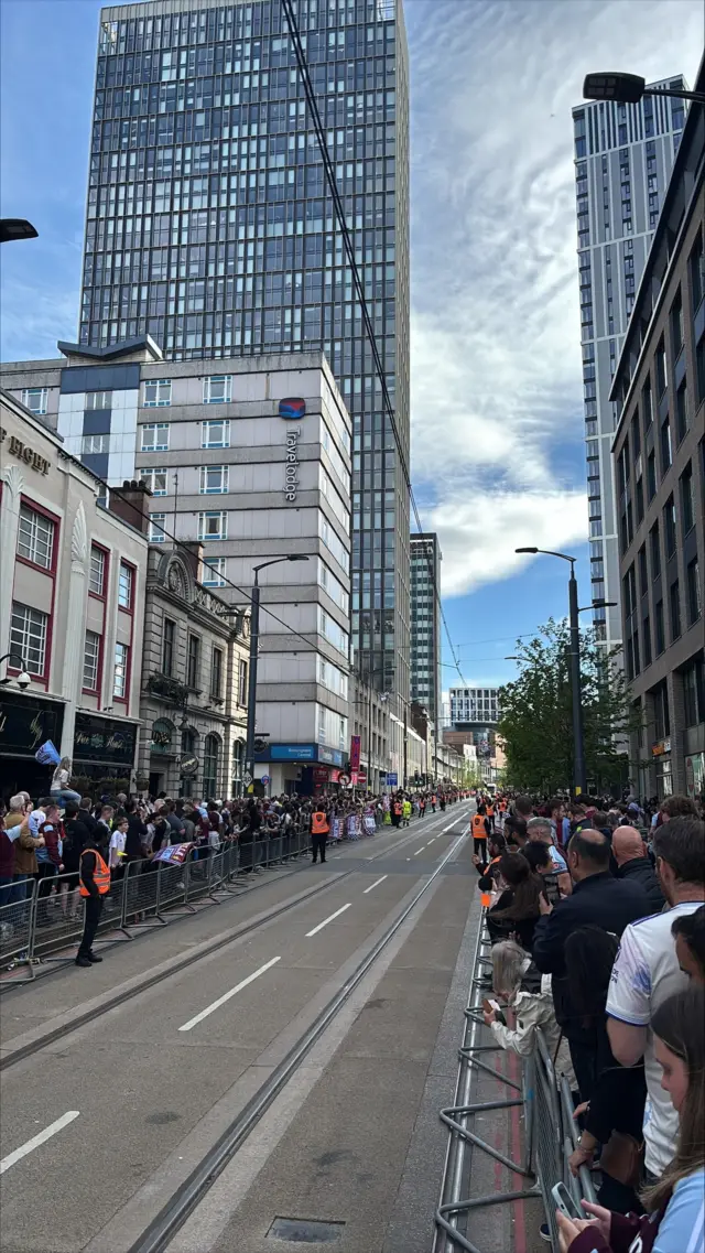People stand along Broad Street as the Villa bus parade approaches