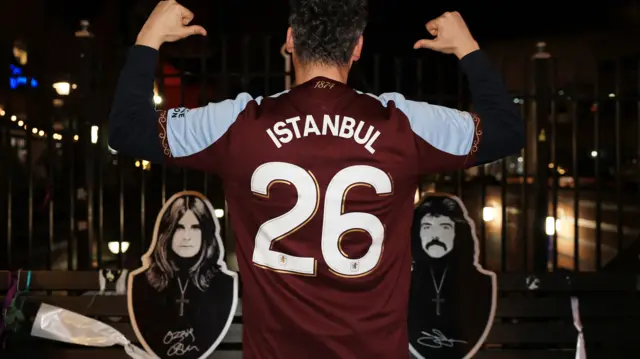 A man wears a Villa shirt, with 'Istanbul 26' on the back