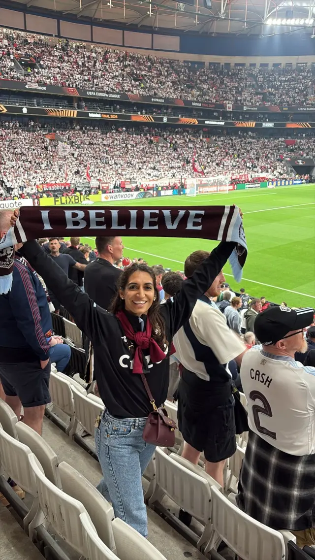 Anaeka holds up a Villa scarf in the stadium