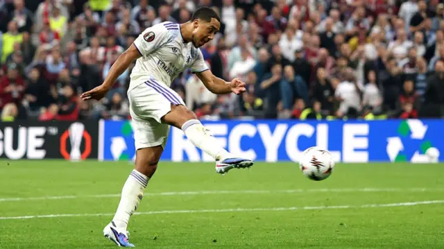 Youri Tielemans volleys a football in a white kit. A side-on shot