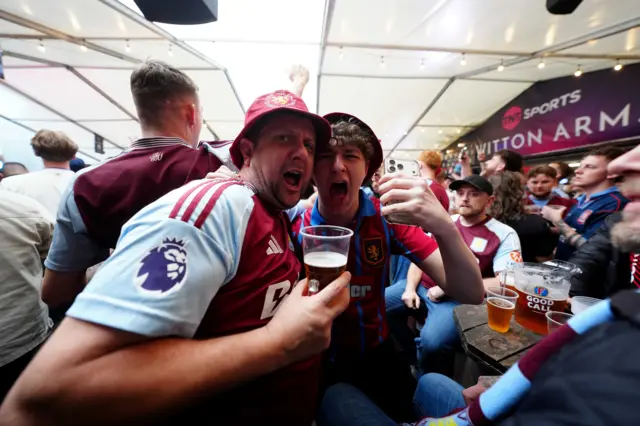 Two Villa fans sit in a pub celebrating the team's win