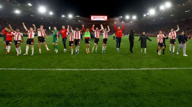 Saints players in red and white celebrating on the pitch