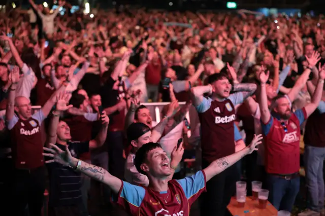 Aston Villa fans hold their arms aloft