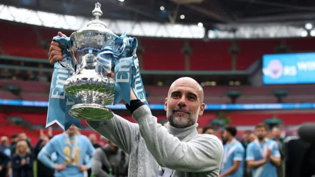 Pep Guardiola, Manager of Manchester City, lifts the Emirates FA Cup trophy a