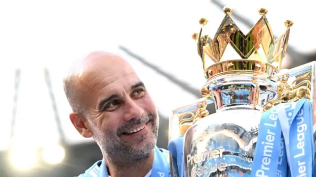 Pep Guardiola, Manager of Manchester City, poses for a photo with the Premier League title trophy
