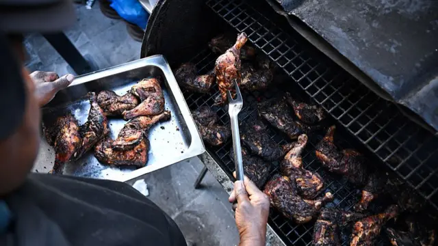 Person plates up chicken from a barbecue.
