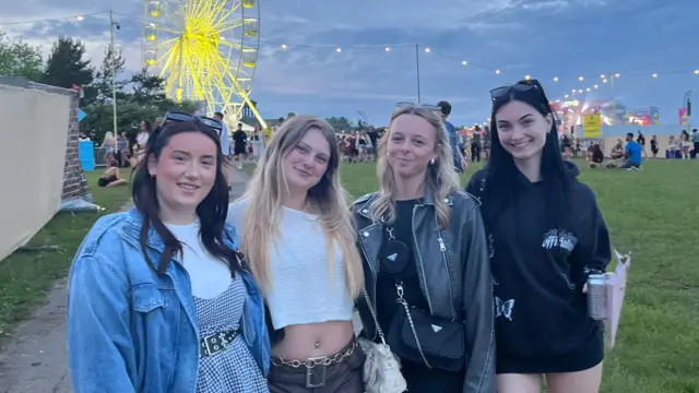 Four girls standing in a field at a festival