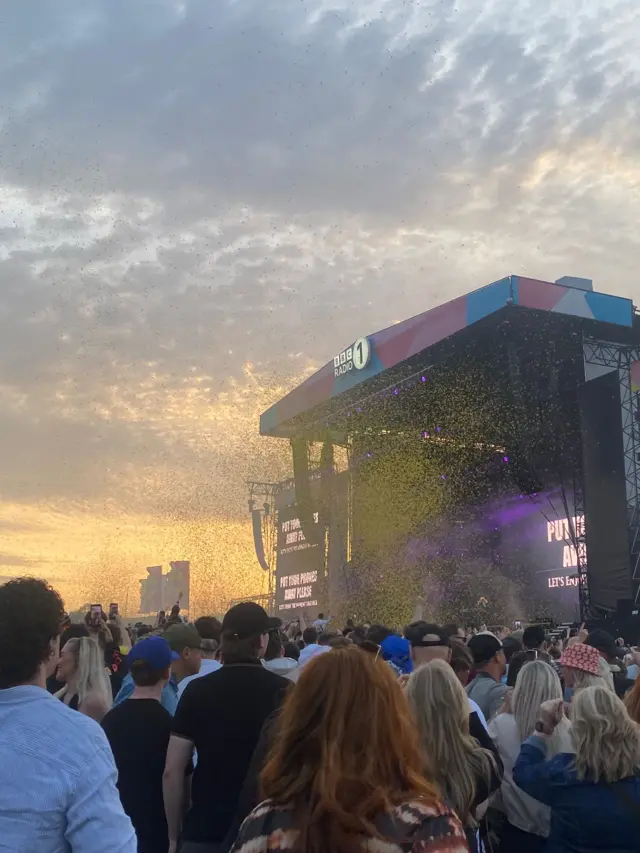 Yellow confetti raining down on a crowd in front of the Big Weekend Main Stage where Fatboy Slim is performing