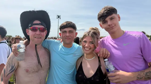 Four people with their arms around each other and smiling