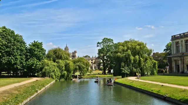 A few punt boats go down the backs on the River Cam in Cambridge