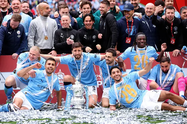 Erling Haaland, Pep Guardiola, Rodri, Ruben Dias, Bernardo Silva, OMar Marmoush, Jeremy Doku and Gianluigi Donnarumma of manchester City celebrate with the trophy
