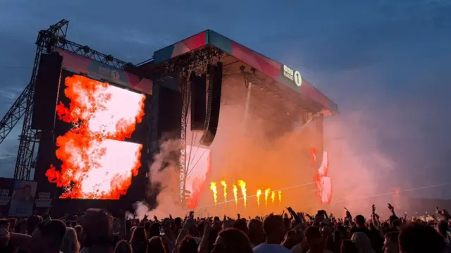 Flames shoot from the stage during Fatboy Slim's set