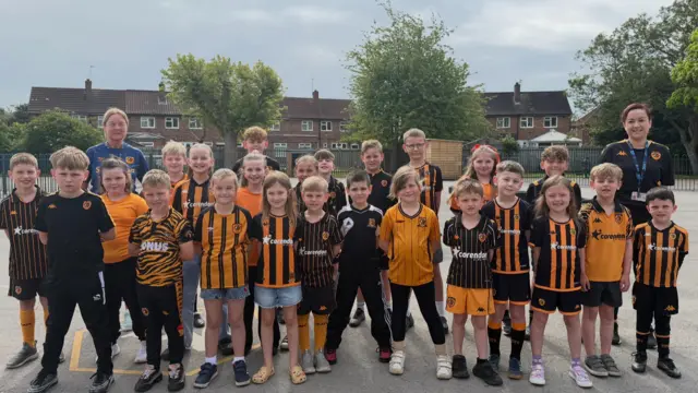 school children wearing Hull City kit standing in a playground