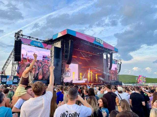 Crowds at the Big Weekend react as pyrotechnics go off on the main stage during FISHER's performance
