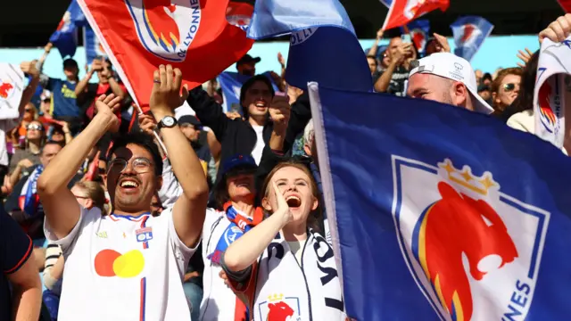 Lyon fans wave flags and bang a drum