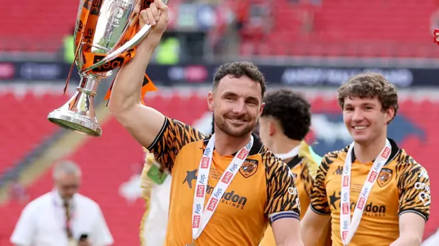 Hull City captain Lewie Coyle holding up the play-off final trophy