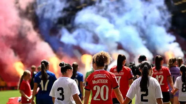 Players make their way out onto the pitch with flares let off in the background
