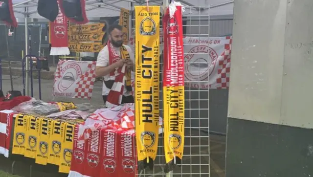 A stall holder is selling scarves - some are half and half - Hull City and Middlesborough