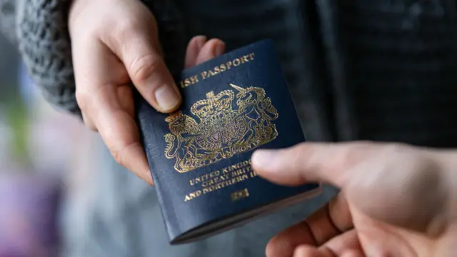 A maan handing a post-Brexit blue British passport