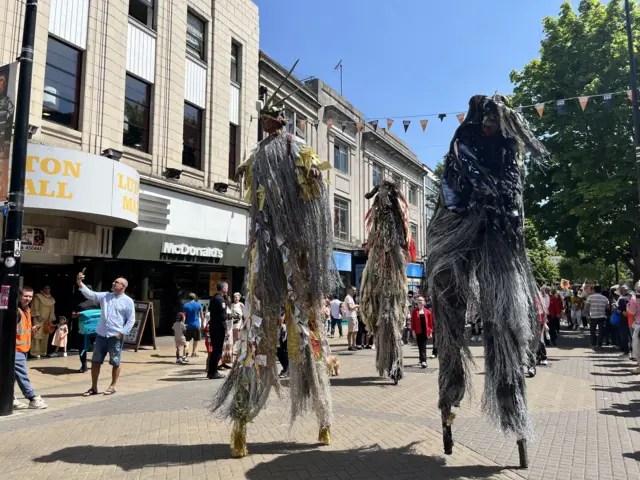 People in shaggy costumes on stilts