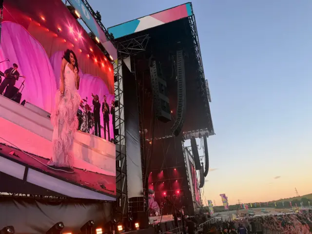 Close up of large festival screen showing Olivia Dean in pink dress