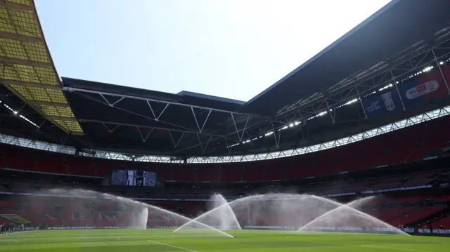 The sun beats down on Wembley, with water sprinklers on spraying the pitch