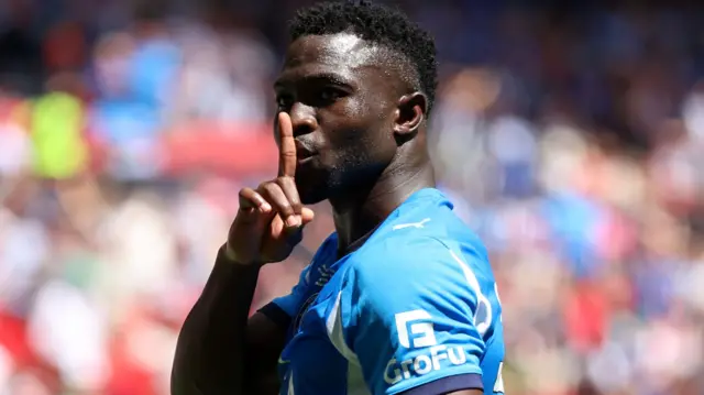 Adama Sidibeh holds his finger up to his mouth