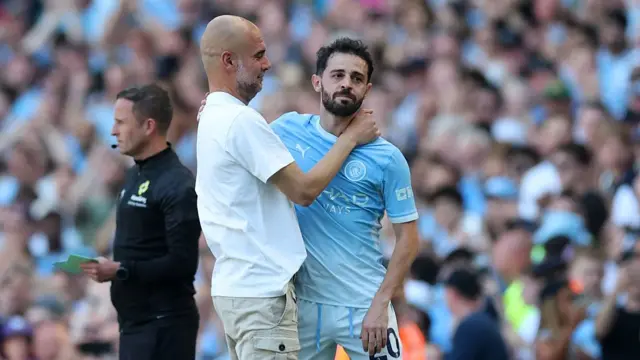 Pep Guardiola, Manager of Manchester City, embraces Bernardo Silva as he leaves the pitch