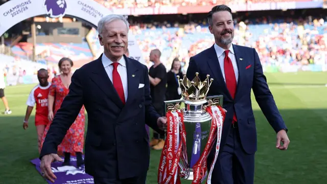 Josh Kroenke and Stan Kroenke walk with the Premier League trophy