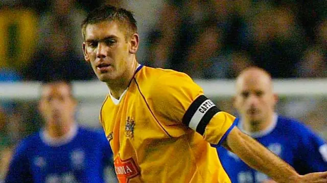 Dave Challinor, wearing a yellow Stockport shirt and the captain's armband, pictured playing in 2003