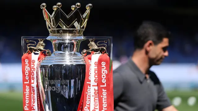 The Premier League trophy with Mikel Arteta in the background