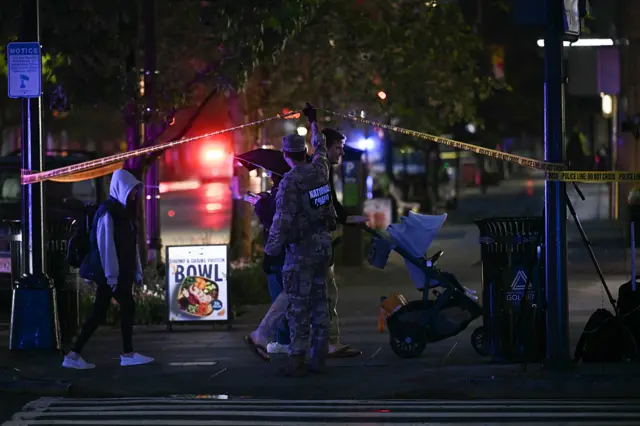 A member of the National Guard guides a family pushing a child in a stroller near the White House after a gunman opened fire in Washington DC.