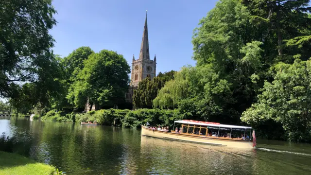 Boat pictured on the water beneath clear blue skies in Stratford-upon-Avon, Warwickshire