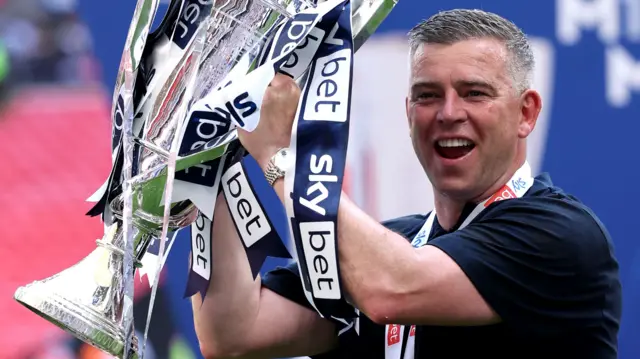 Bolton Wanderers boss Steven Schumacher holding the trophy