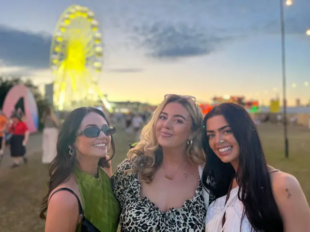 Amy, Meghan and Deborah. Amy has black hair and is wearing sunglasses and smiling. Meghan has blonde hair and a black and white dress. Deborah has black hair and is wearing a white top.